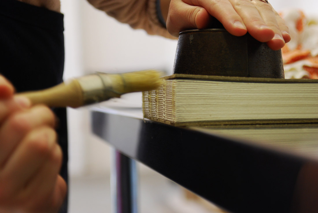 Artist applying glue to the spine of a binding.