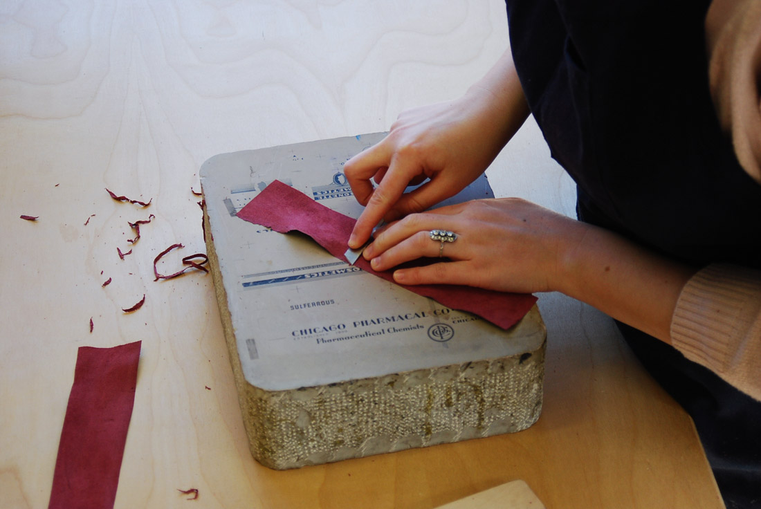 Artist paring leather by hand for a binding.