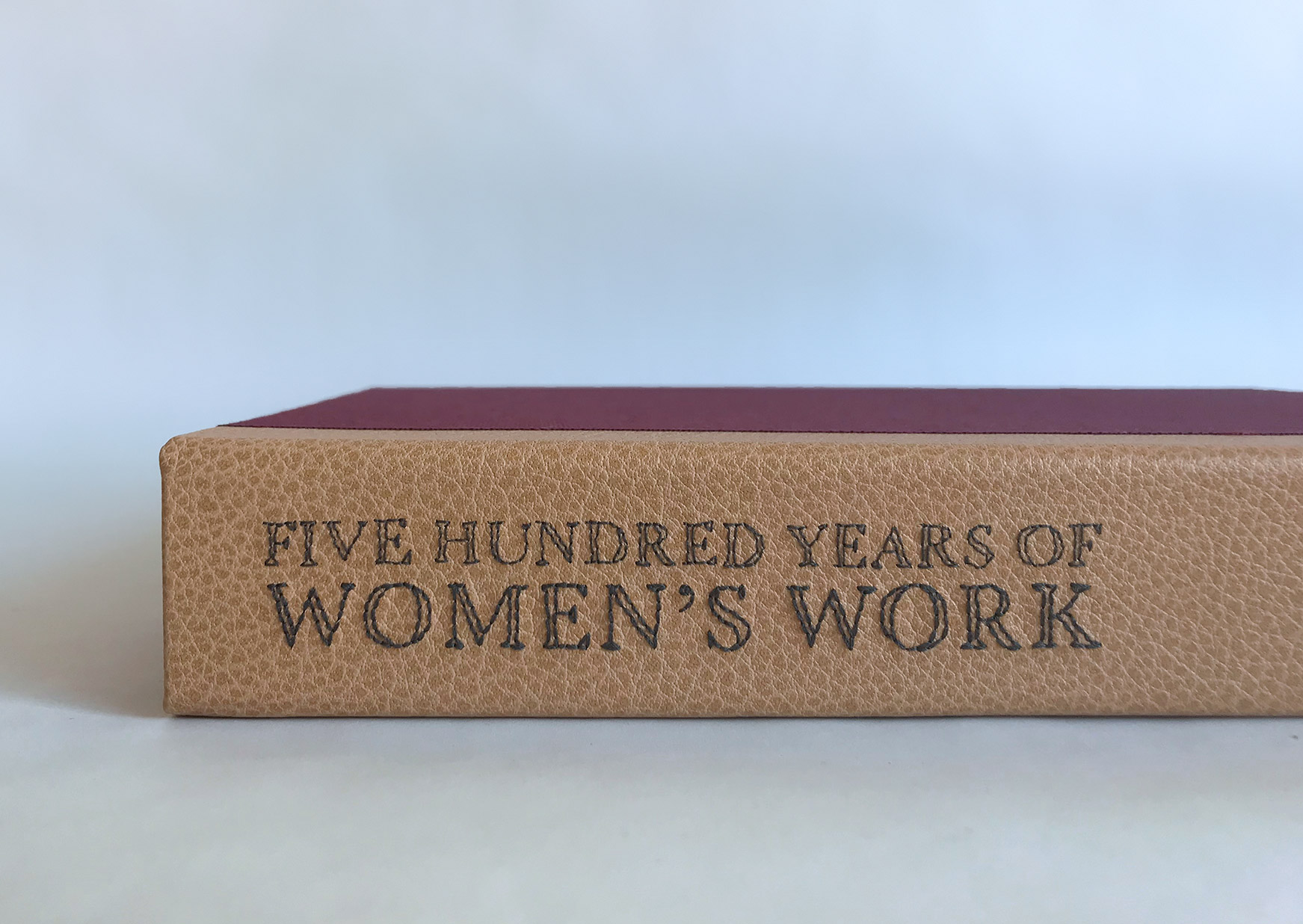 Spine of Five Hundred Years of Women’s Work binding on a white table.