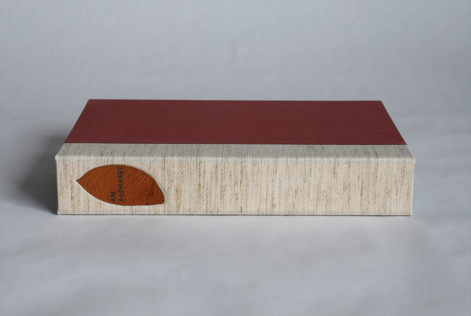 Box spine of An Alphabet binding on a white table.