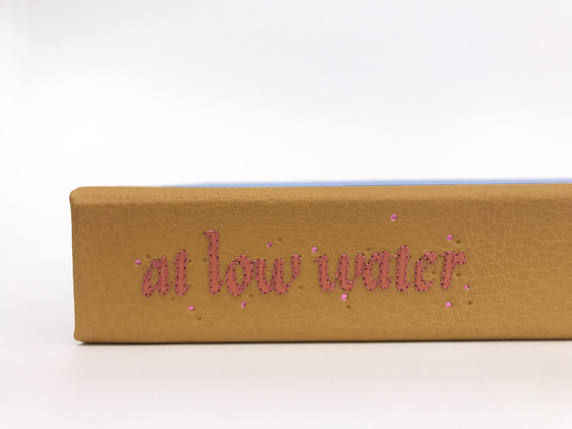 Close-up of box spine of At Low Water binding on a white table.