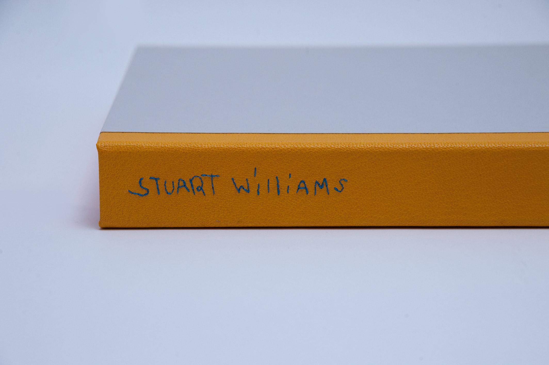 Box spine of Stuart Williams binding on a white table.