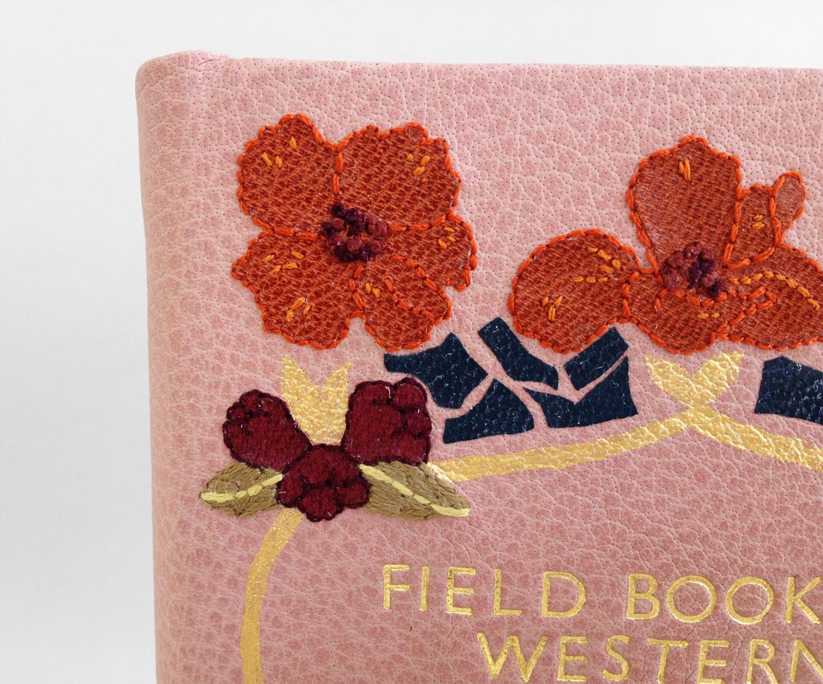 Close-up of front cover of Field Book of Western Wild Flowers binding on a white table.