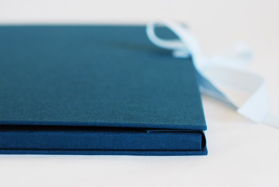 Edge of a blue portfolio sitting on white table.