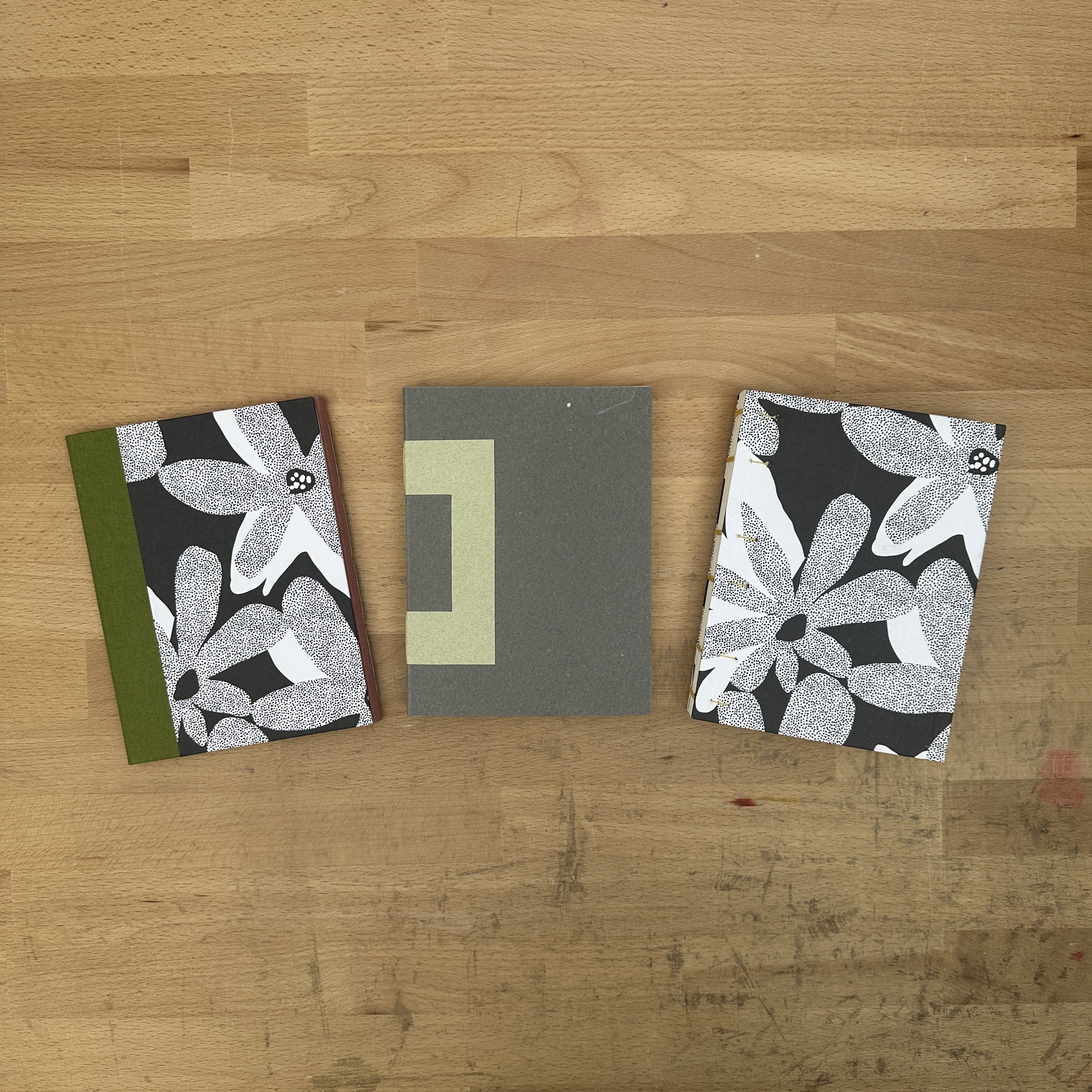 Three books laying flat on a wooden table.