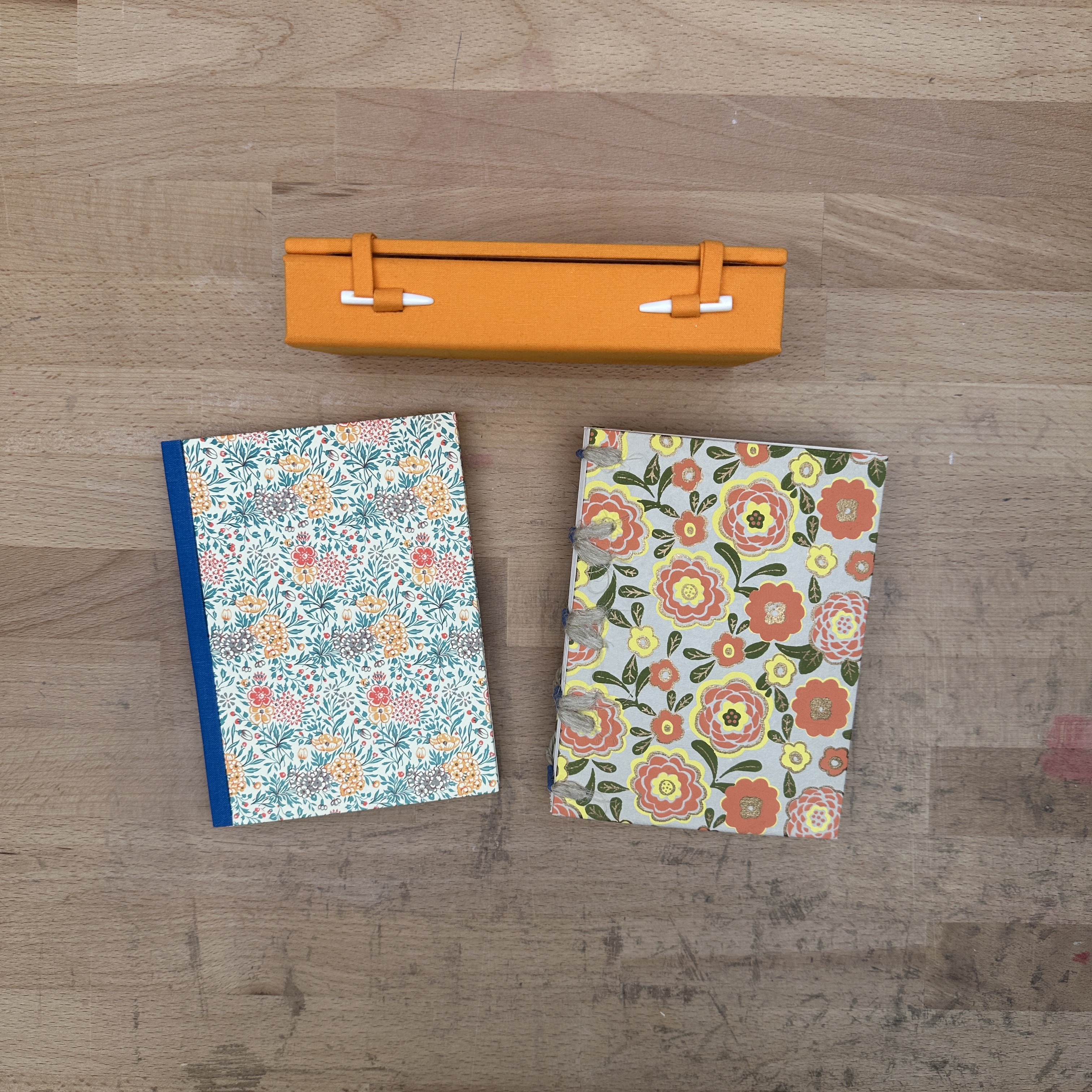 Two books and one box laying flat on a wooden table.