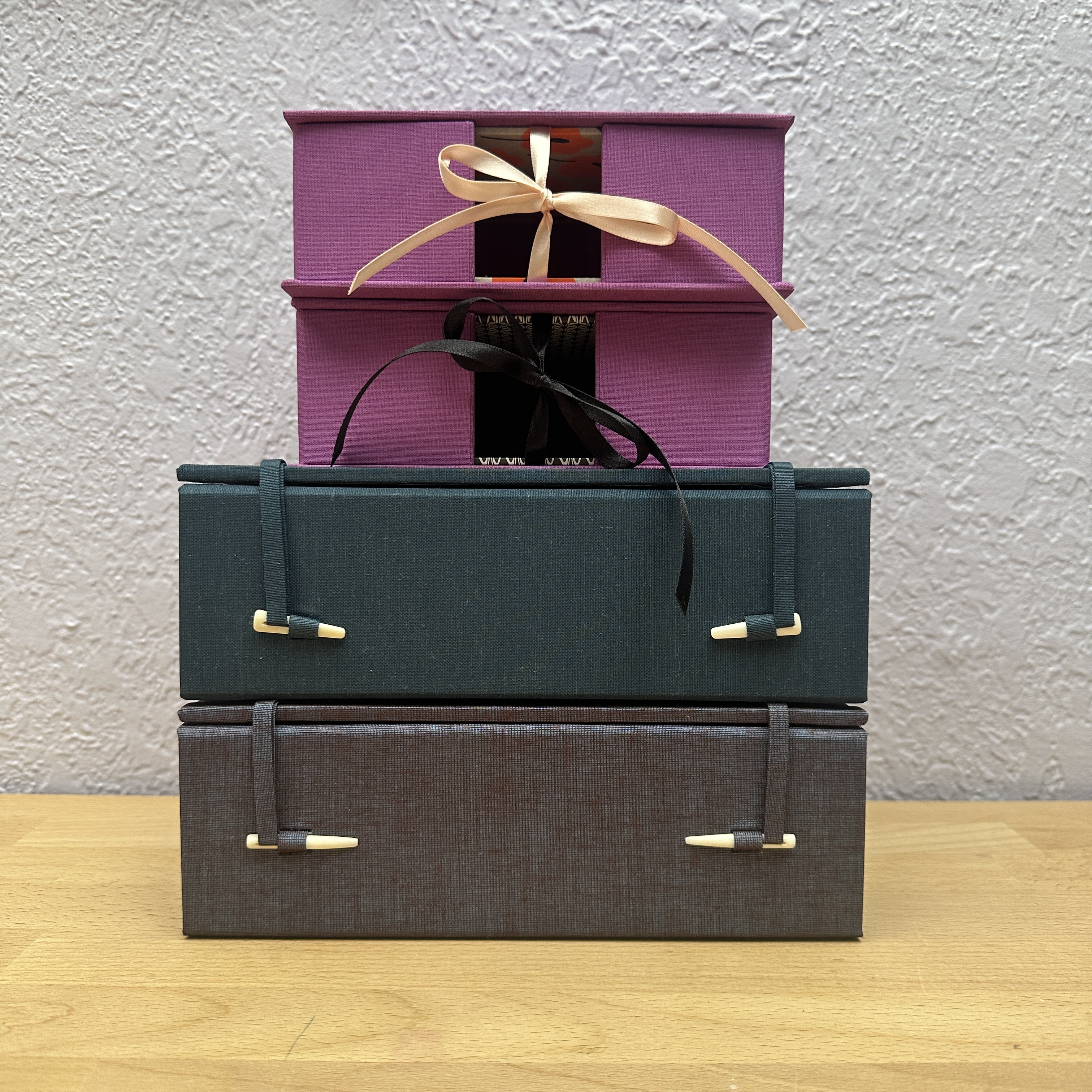 Four boxes stacked ontop a wooden table.