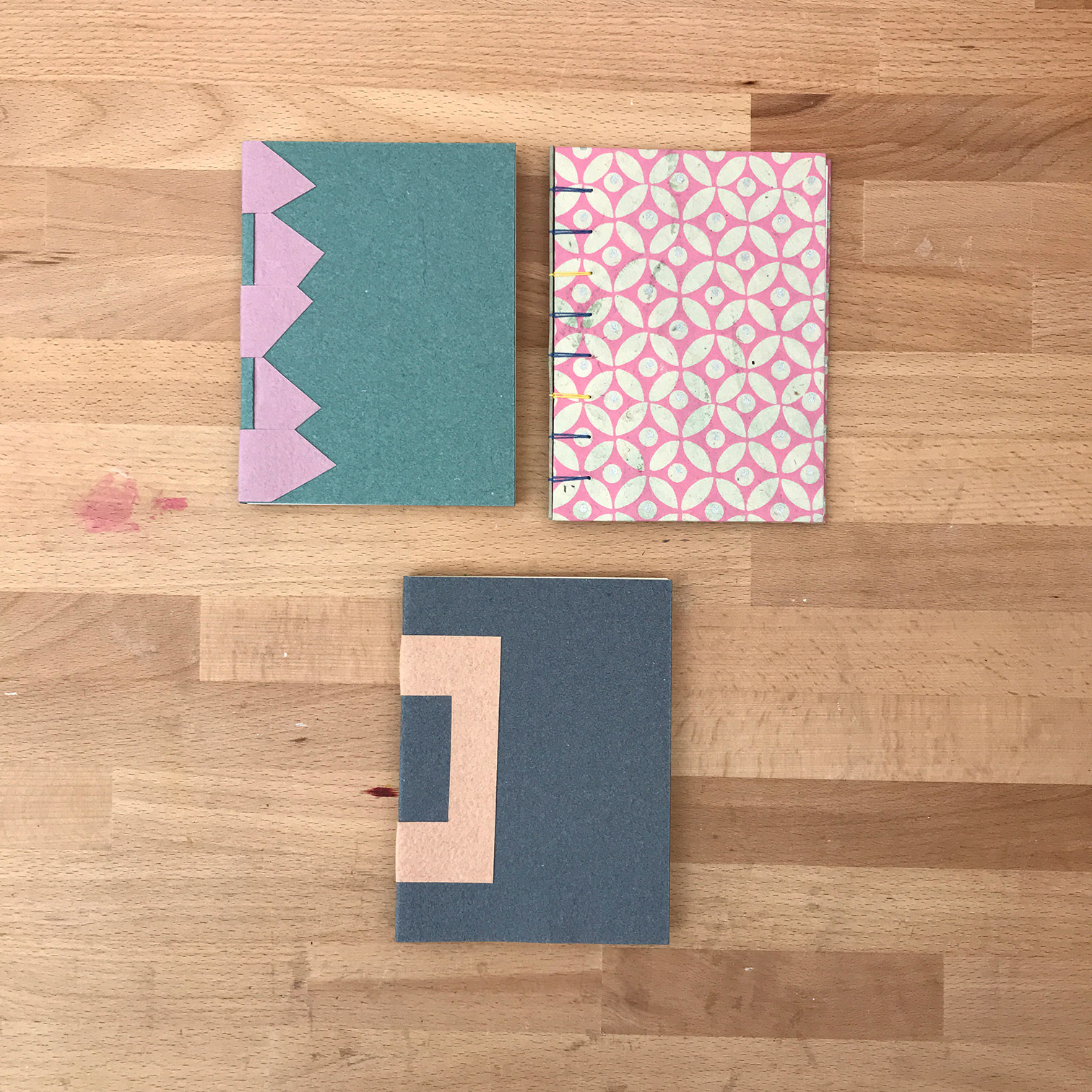 Three cross structure bindings laying flat on a wooden table.