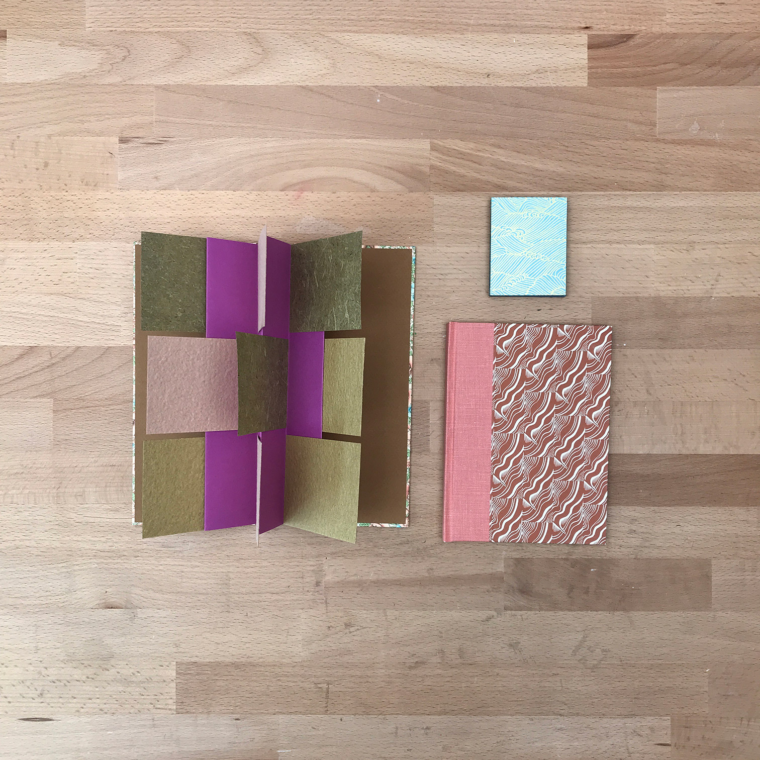 Three books laying flat on a wooden table.