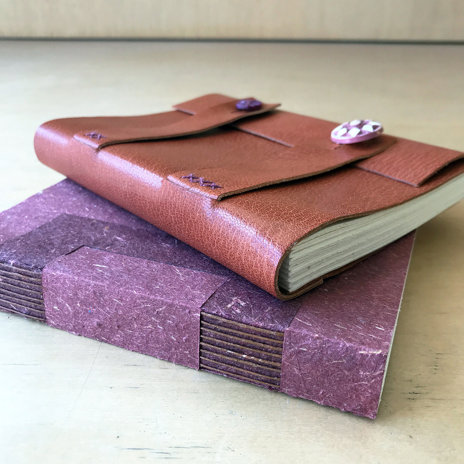 Paper and leather Cross Structure bindings sitting on a wooden table