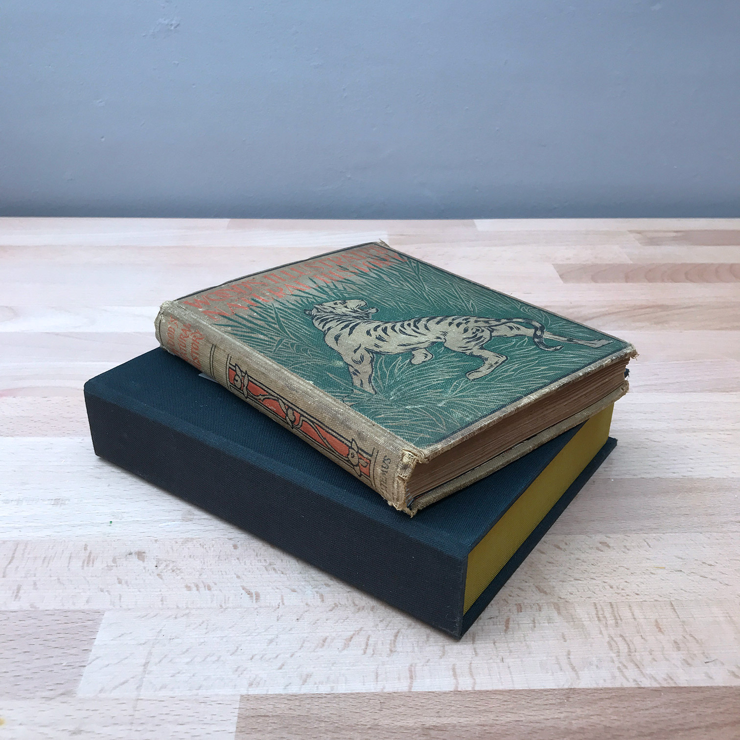 Clamshell box and a book stacked on a wooden table.