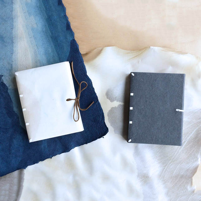 Limp Vellum Binding and paper case binding laying on a wooden table.