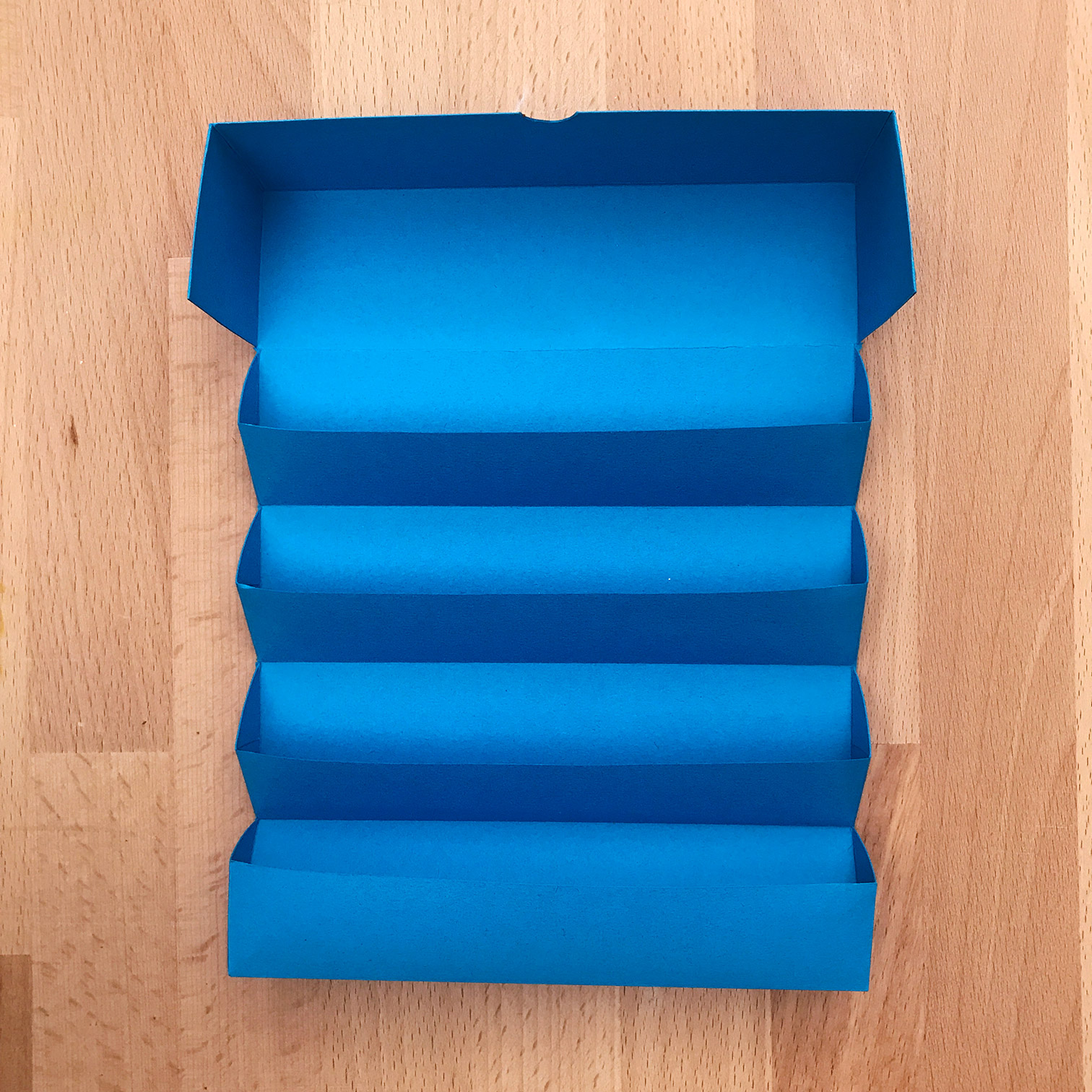 Top view of a blue Quick Enclosure sitting on a wooden table.