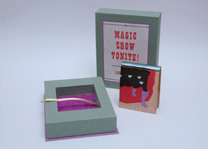 A miniature book standing next to a telescoping box sitting on a table.