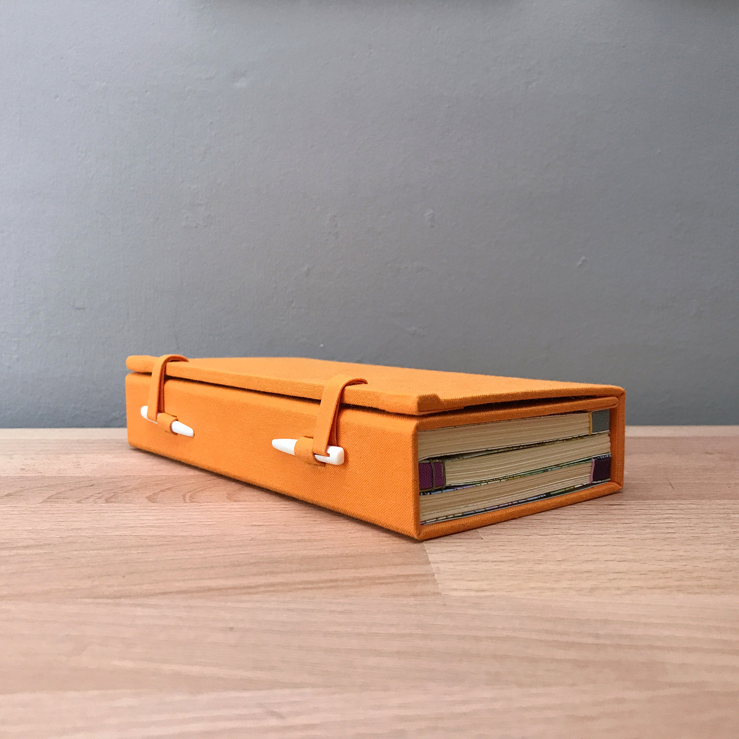 Japanese Bindings sitting within a wraparound case sitting on a wooden table.