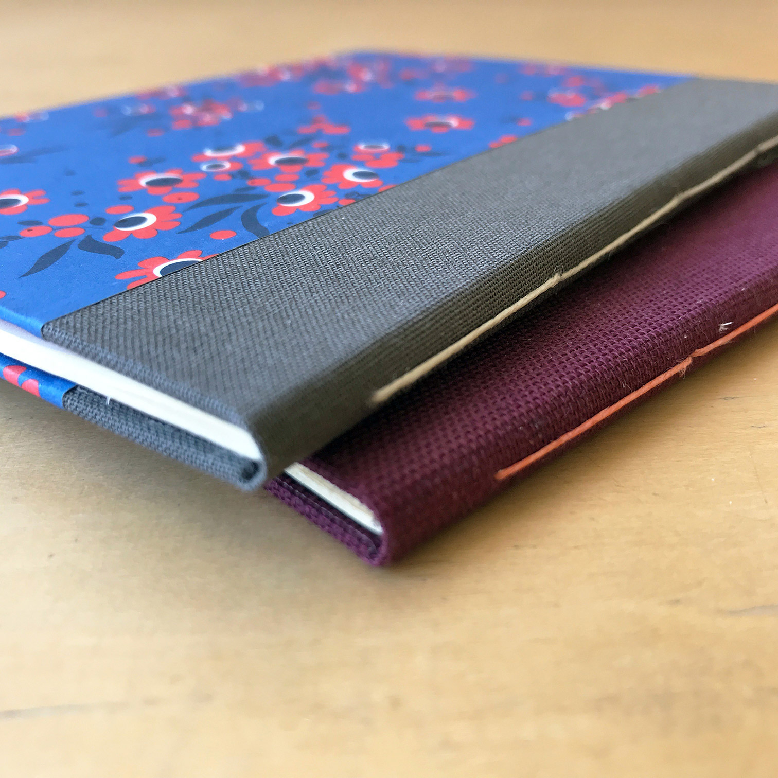 The spines of a variety of Single Signature Bindings on a wodden table.