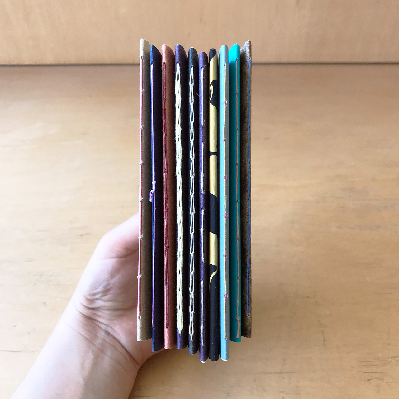 Artist showing the spines of a variety of Single Signature Bindings.